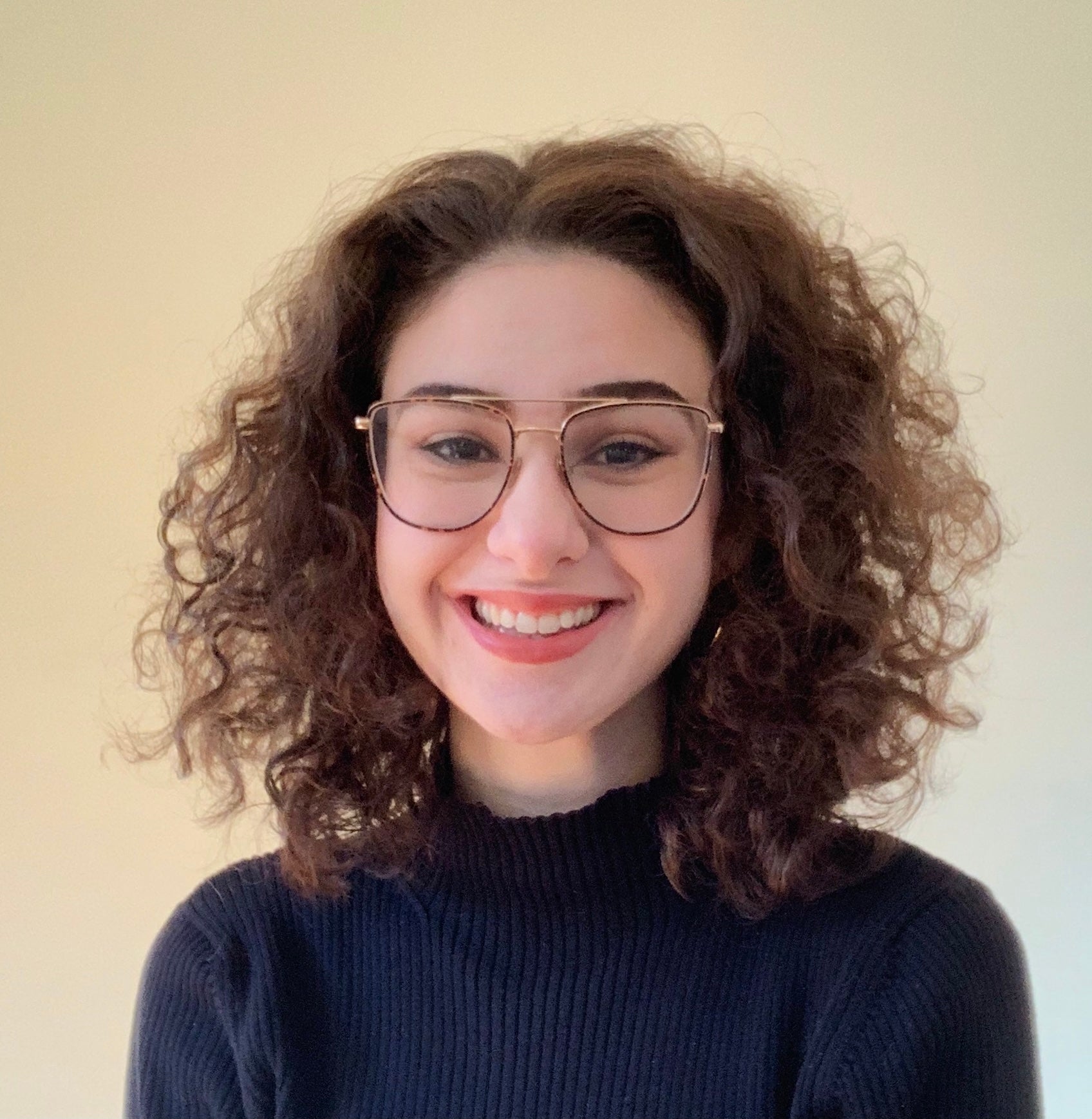 Headshot of Madeline Fox, white skin, glasses, curly brown hair