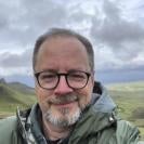 Jeff Oaks, light skin, graying hair, beard with gray sky and pasture behind him