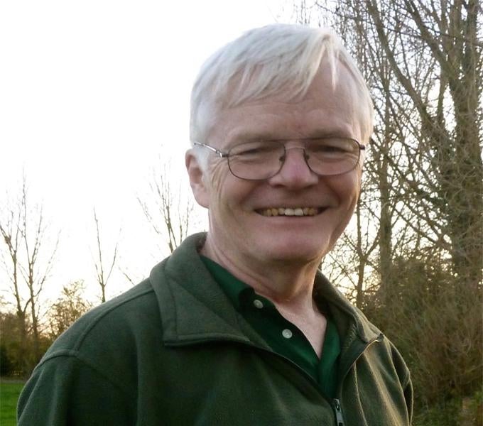 Stephen Carr, a white man with white-blonde hair, smiling outdoors, a tree in the background