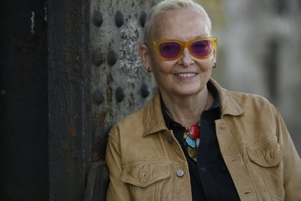 Jan Beatty, a white woman wearing a tan jacket, with close-cropped blond hair and dark orange glasses